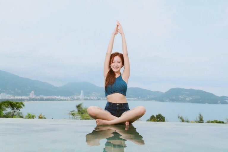 Young woman doing yoga by a scenic waterfront, enjoying a serene landscape.