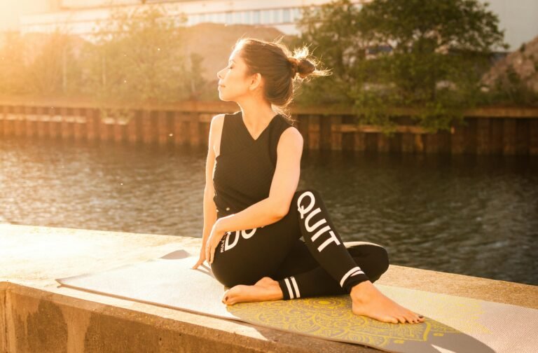 Woman practicing yoga at sunset by a serene river in Gamla Staden, Sweden.